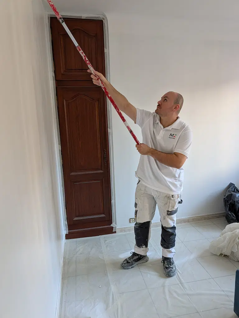 rtisan peintre de M2Peinture en cours d'application de peinture sur un mur intérieur à Marseille, illustrant les services de rénovation et finition.